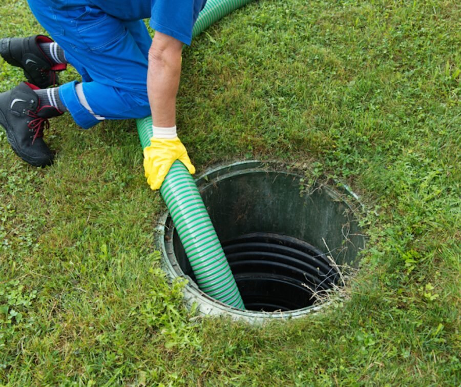 Guiding the pump hose into an opened septic tank on a job.